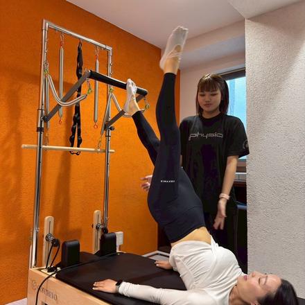 タワーのバーに足をかけ、脚を高く伸ばして背骨を持ち上げる種目